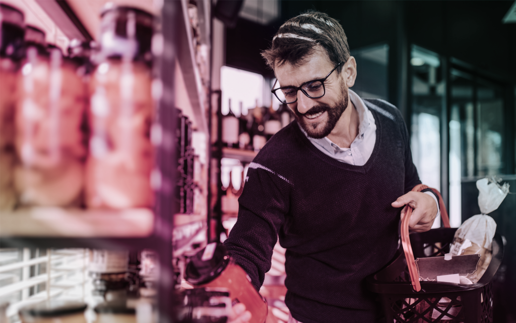 a man shopping, he is looking at a jar of food