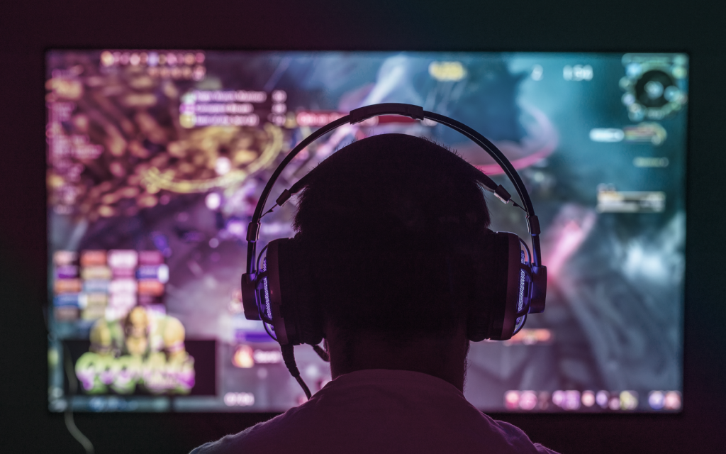 a man wearing a headset sits in front of a computer screen