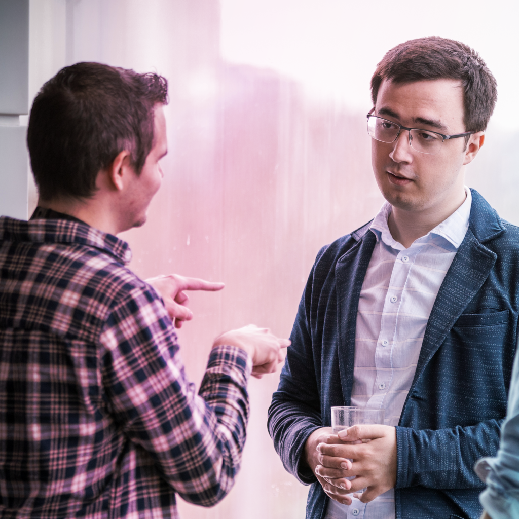 two men discussing something, one is holding a glass of water