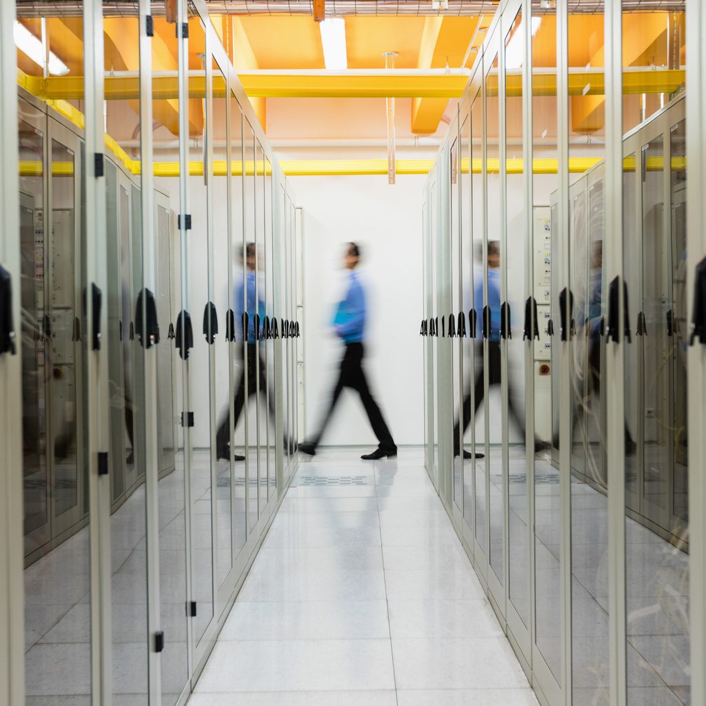 a man walking between two server stacks